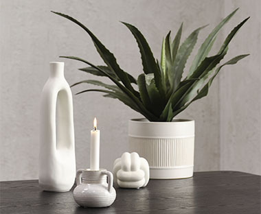 Dekorace v bílé barvě: svícen, svíčka, váza, květináč a umělá rostlina