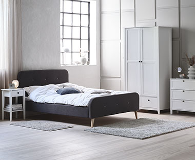 Ložnice s čalouněnou postelí a dřevěnou šatní skříní, noční stolkem a komodou
