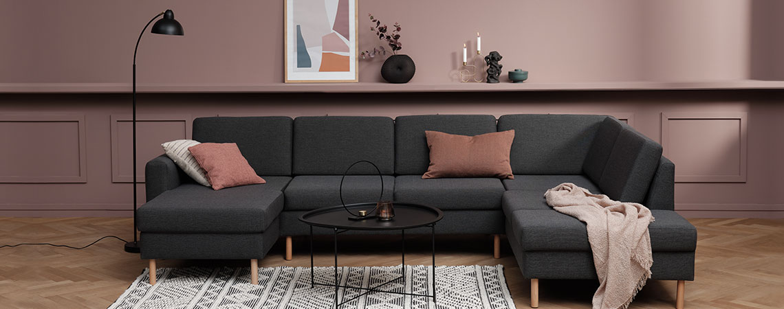 Velká šedá rohová pohovka s polštáři a dekou v moderním obývacím pokoji