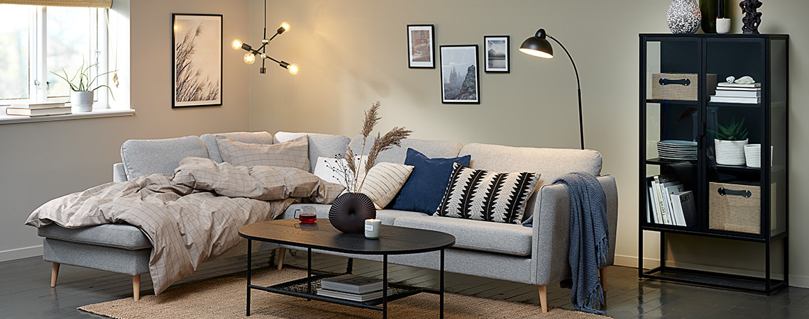 Hygge v obývacím pokoji s velkou rohovou pohovkou, polštáři a osvětlením.