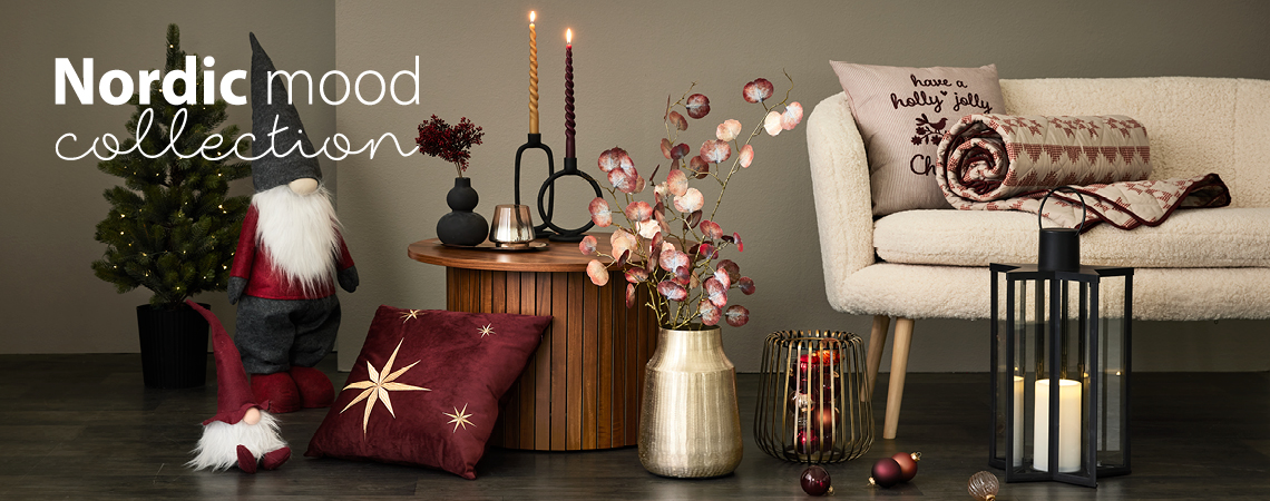 Vánoční skřítci, dekorační polštáře, zlatá váza s umělou květinou, zlatý svícen a černá lucerna před bílou pohovkou