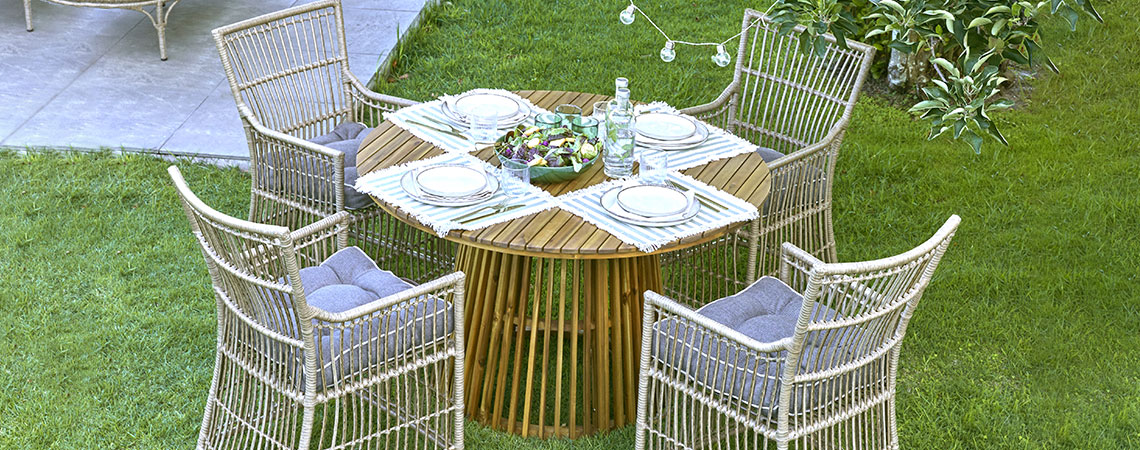 Kulatý zahradní stůl a čtyři zahradní židle na trávníku