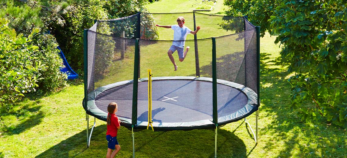 Děti si hrají na velké trampolíně na zahradě
