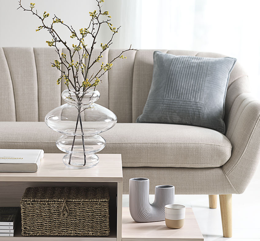 SYLVESTER clear vase, TORMUND vase, and FREDERIK mug Bright living room with playful vases on coffee table and beige sofa
