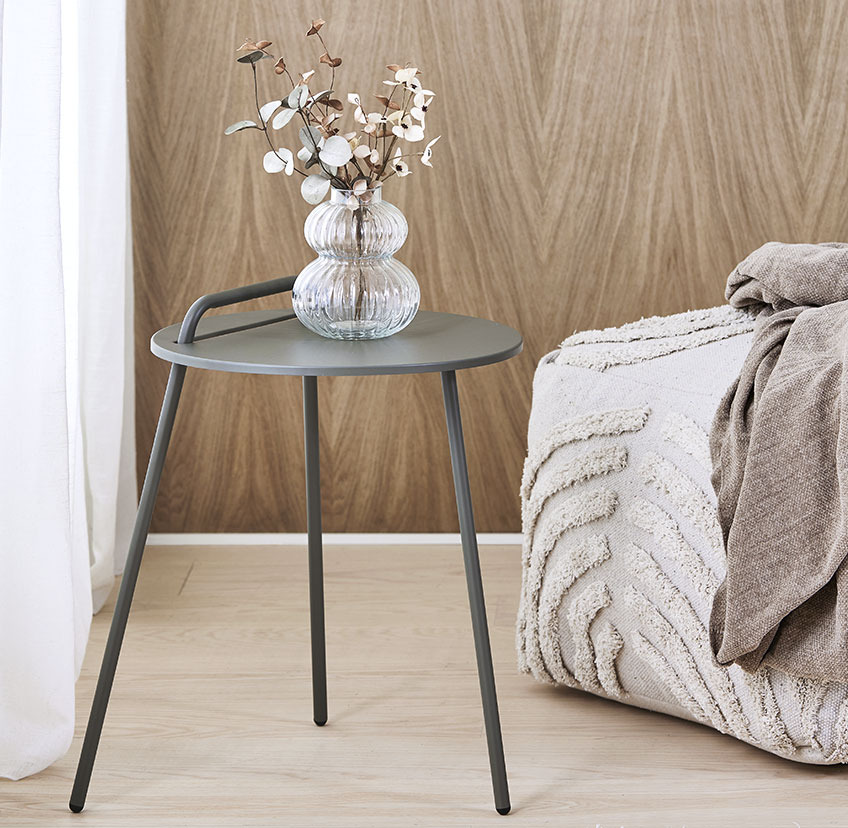STAE minimalistic end table in grey and HYLKE pouffe in light beige Minimalistic end table with three legs and handle and light beige pouffe with soft, patterned surface