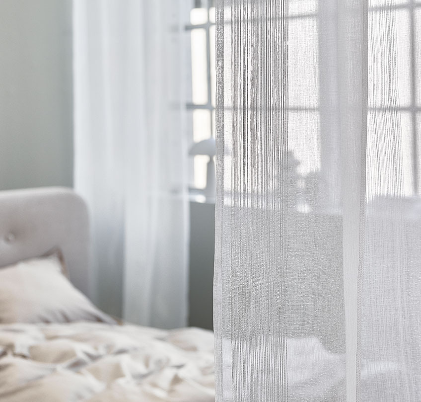 Rose coloured curtains used to separate a sleeping area from a large living room 