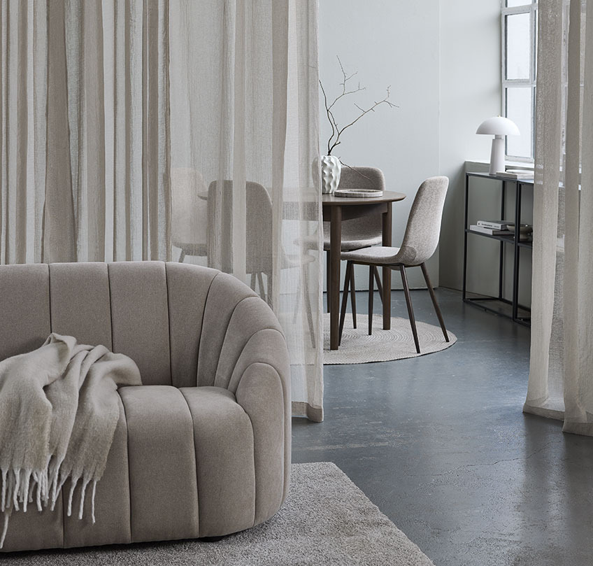 Blue curtain behind a sofa separates a living area from a dining area 