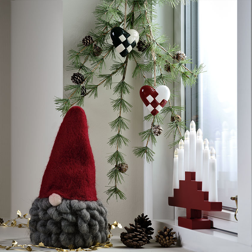 The MUGGLESTEN Christmas elf has a big, curly beard Scandinavian Christmas elf with grey beard on a decorated windowsill