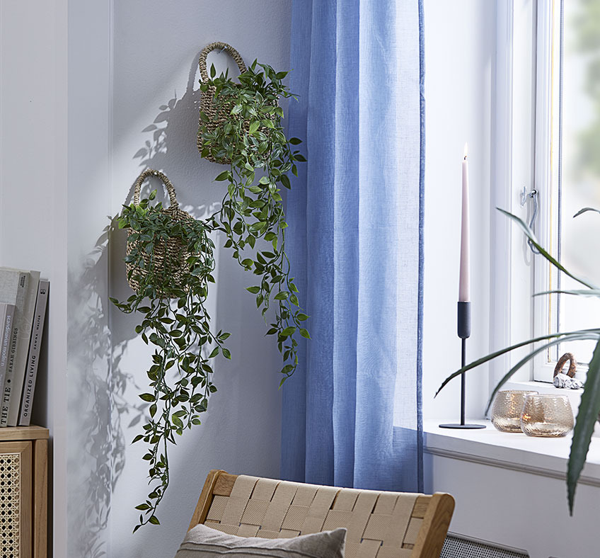 Dva koše s umělými rostlinami zavěšené na obývací stěně