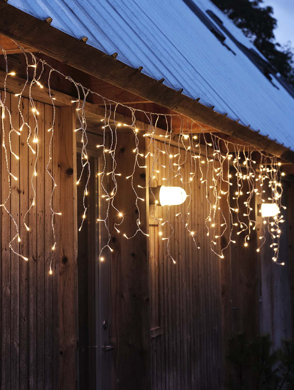 Světelný řetěz SNOTRA se zabudovaným časovačem Světelný řetěz zářící ve tmě zavěšený na fasádě