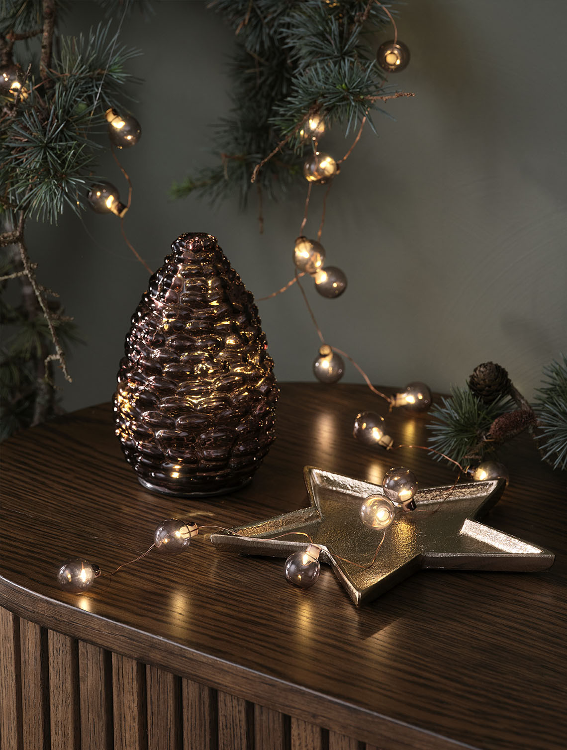 Šiška DELLING a světelný řetěz ALV Dekorativní vánoční osvětlení - skleněná šiška a světelný řetěz se zlatými ozdobami na příborníku