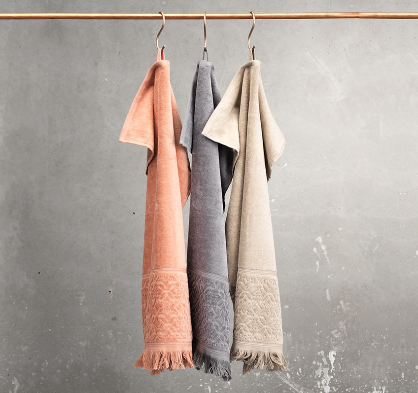 SVANESUND towels in 100% cotton are available in different colours Rose, sand and grey towel hanging from a rail