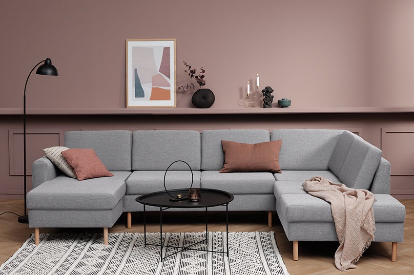Large grey corner sofa with cushions and a throw in a modern living room 