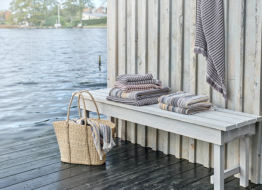 Luxusní ručníky na lavičce a v košíku u jezera