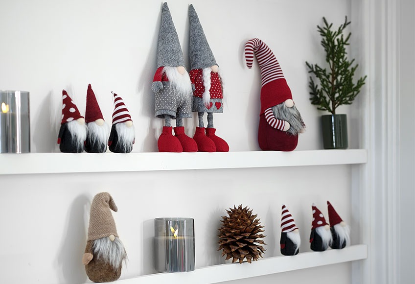 Elves in red and beige on shelf with pinecone and candles 