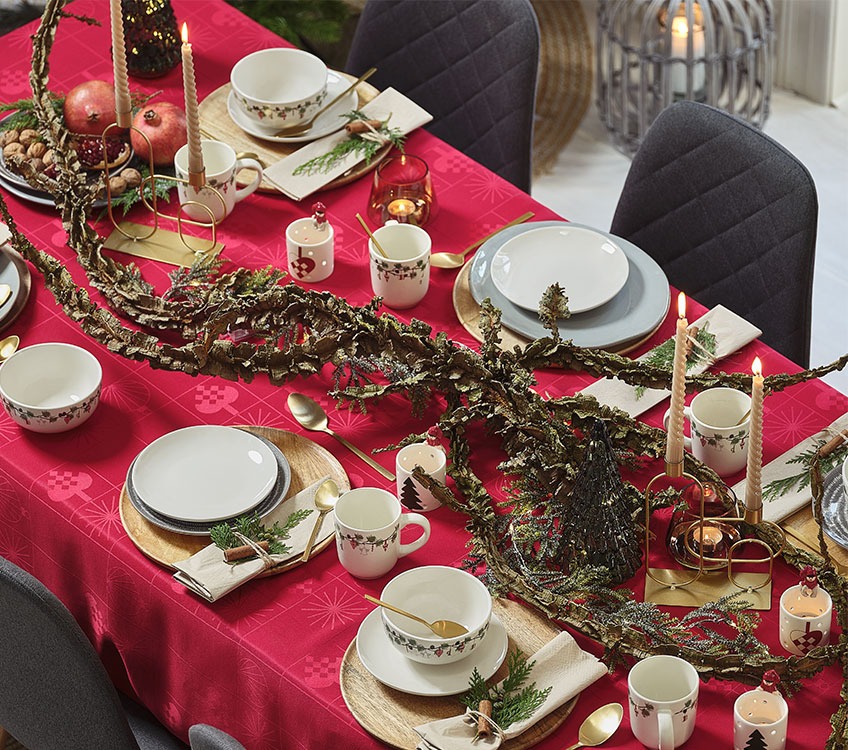 Christmas dinner setting with red tablecloth and gold cutlery 