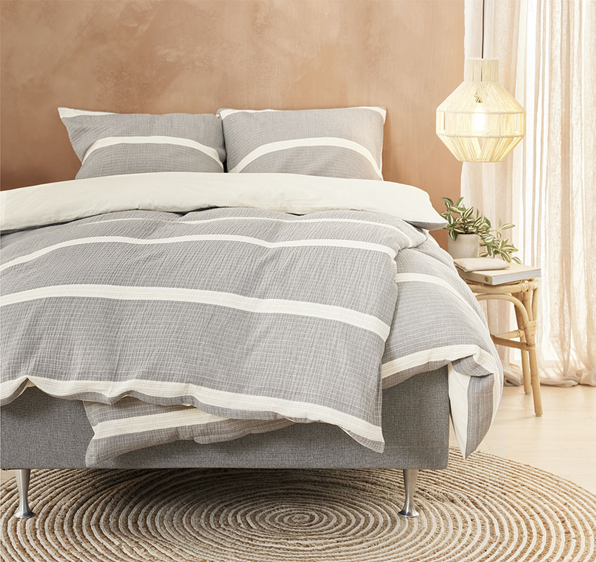 Bed with bed linen in grey or beige colours 
