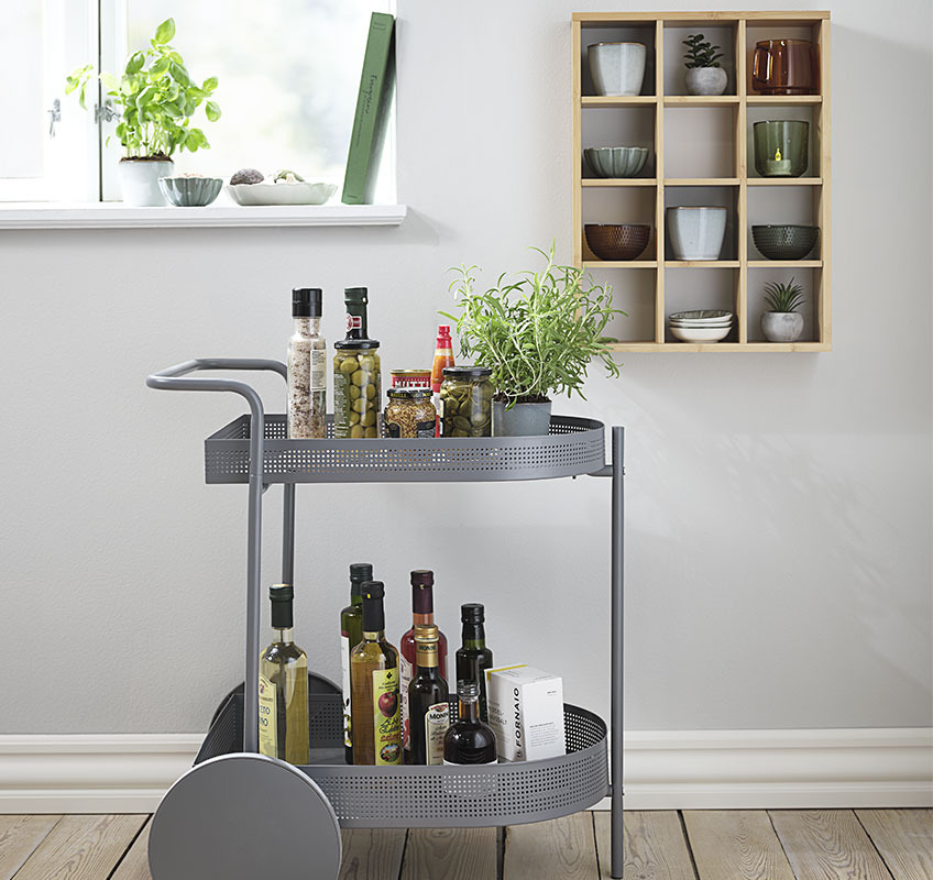 Grey trolley styled with kitchens items and wall shelf displaying mugs and bowls