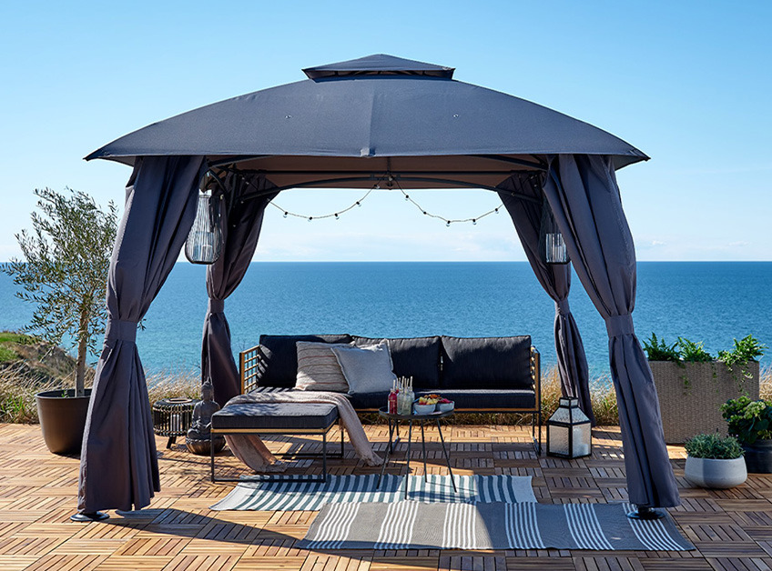 Grey gazebo with lounge set and decorations overlooking the sea 