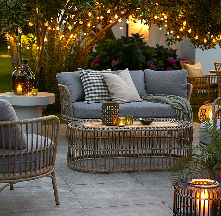 Comfortable lounge furniture on patio with string lights, battery lamps, and lanterns with candles and tealights