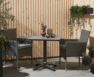 Sort cafebord med to stabelstole på en terrasse